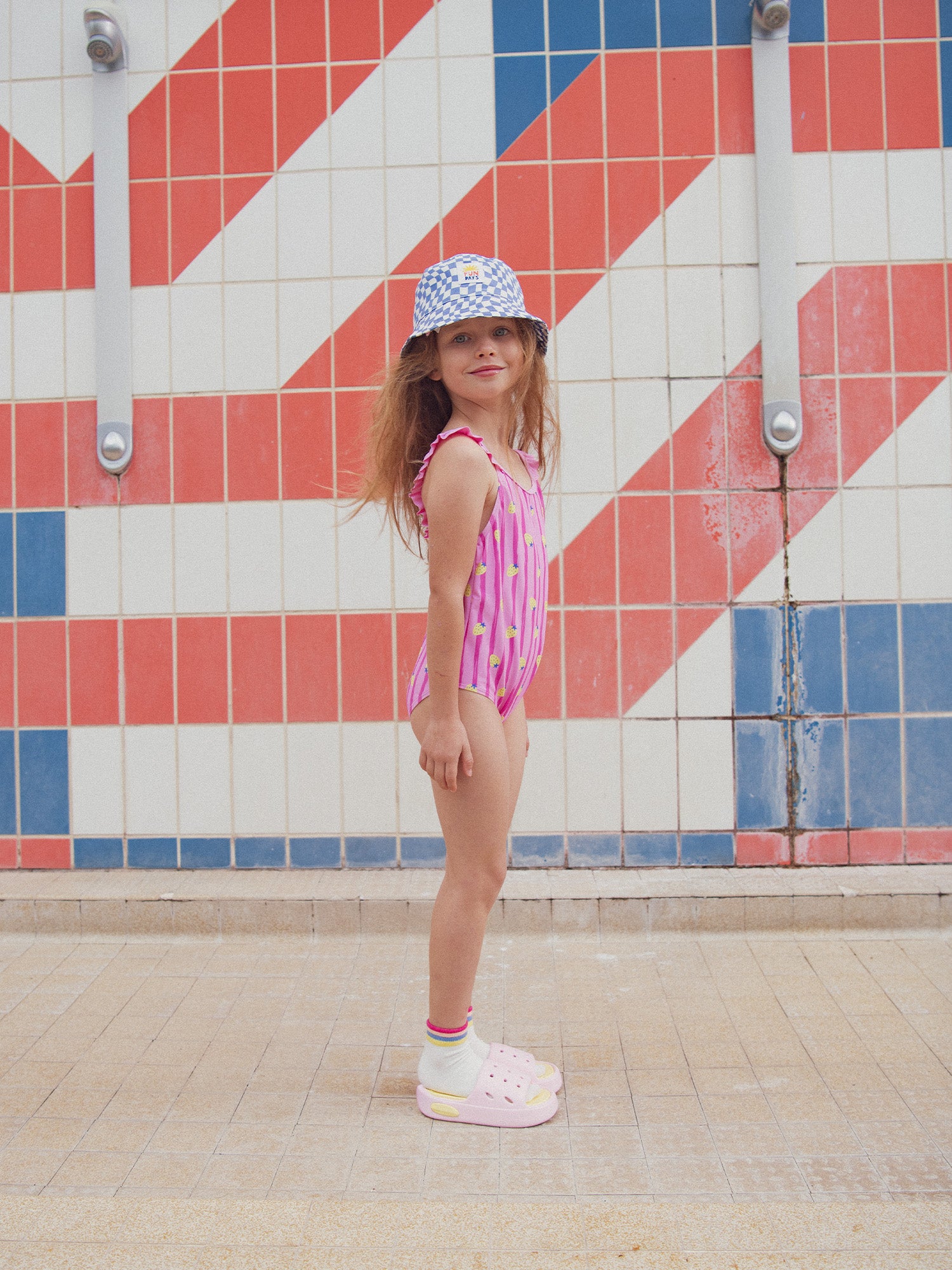 One-piece pink swimsuit printed with strawberries and stripes
