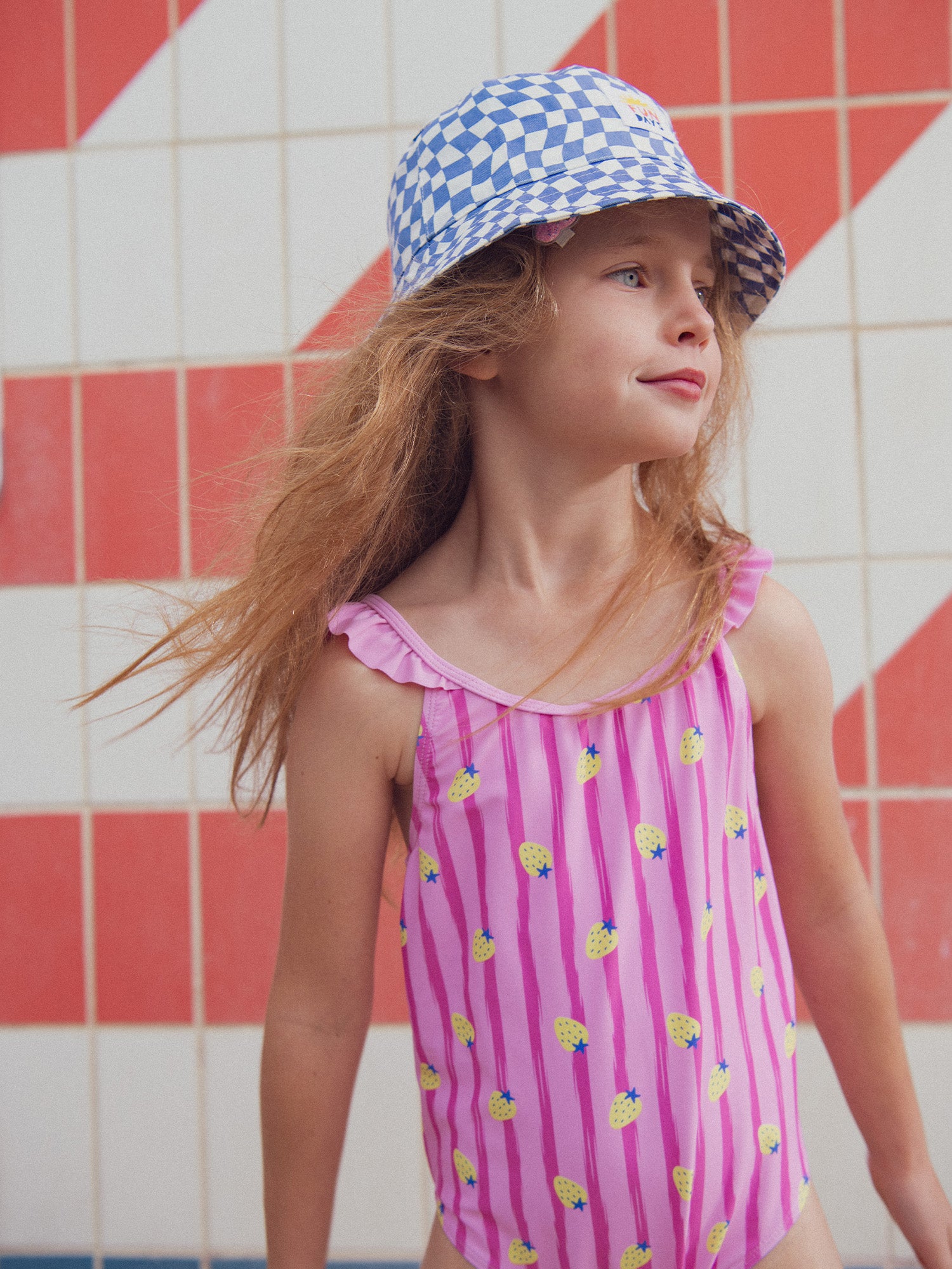 One-piece pink swimsuit printed with strawberries and stripes