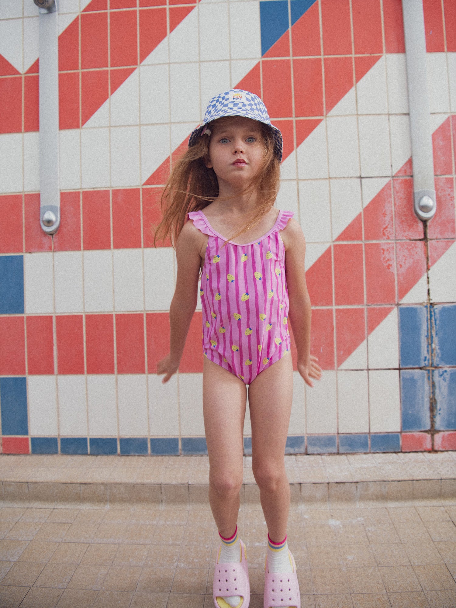 One-piece pink swimsuit printed with strawberries and stripes